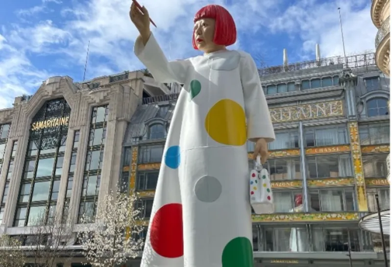 Statue of a woman wearing a poka-dot dress and holding a paint brush.