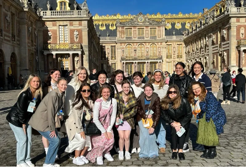 Students posing in front of a large ornate building while studying abroad.