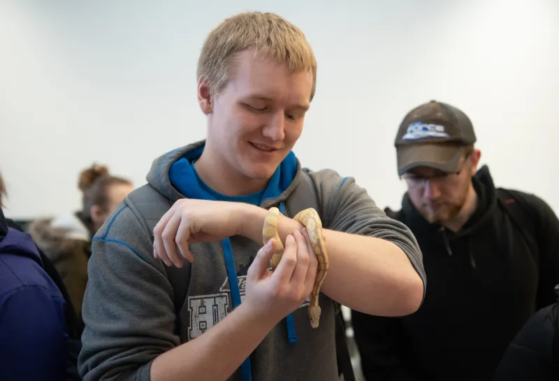 Students holding a snake at the NDSU Darwin Days Evolution Pop-Up Museum