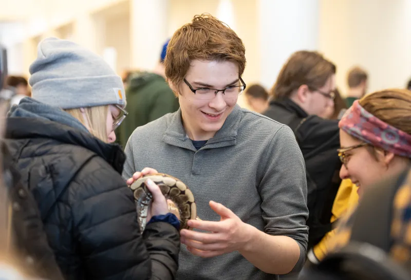 Students holding a snake at the NDSU Darwin Days Evolution Pop-Up Museum