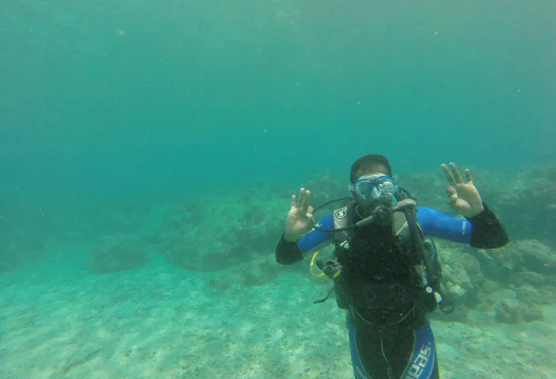 Sekhar scuba diving and waving to camera.