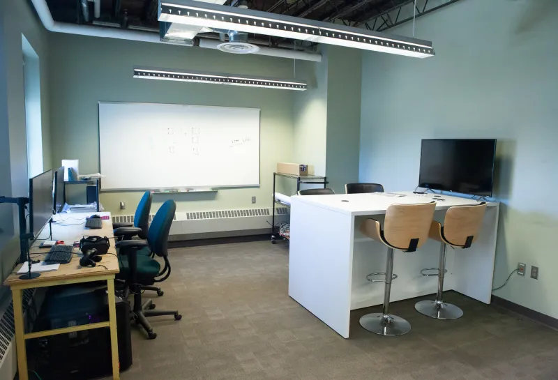 Classroom with desks, chairs, whiteboard and computers in Klai Hall 