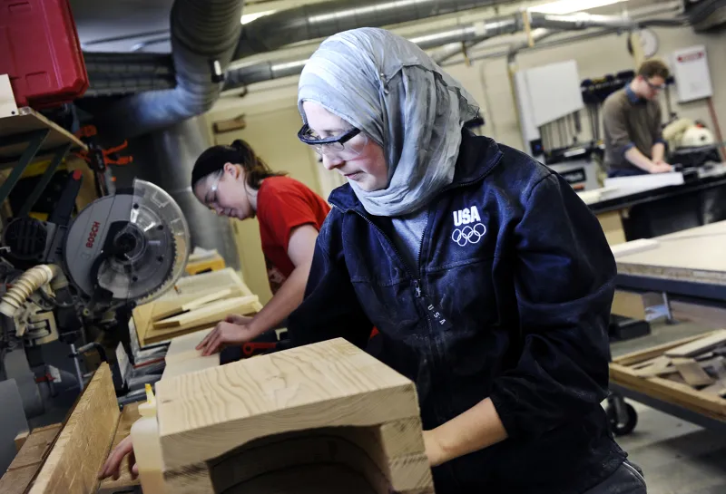 Student wearing protective eyeware while working with wood in woodship.