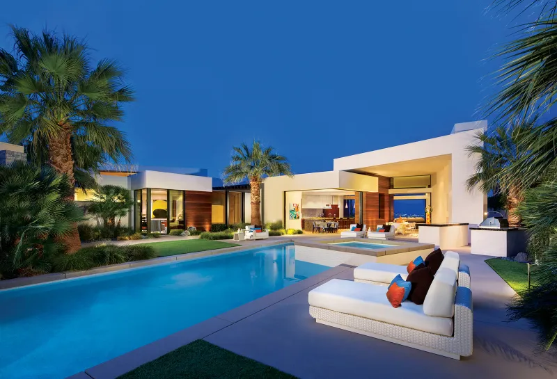 Pool area with louge chairs, porch, hot tub, palm trees just off the main home.