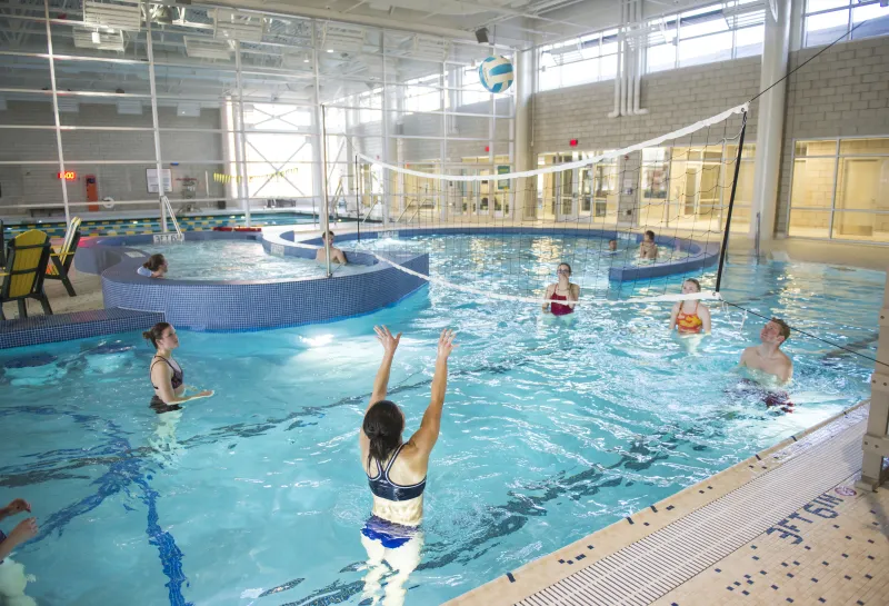 Students playing volleyball in leisure pool 