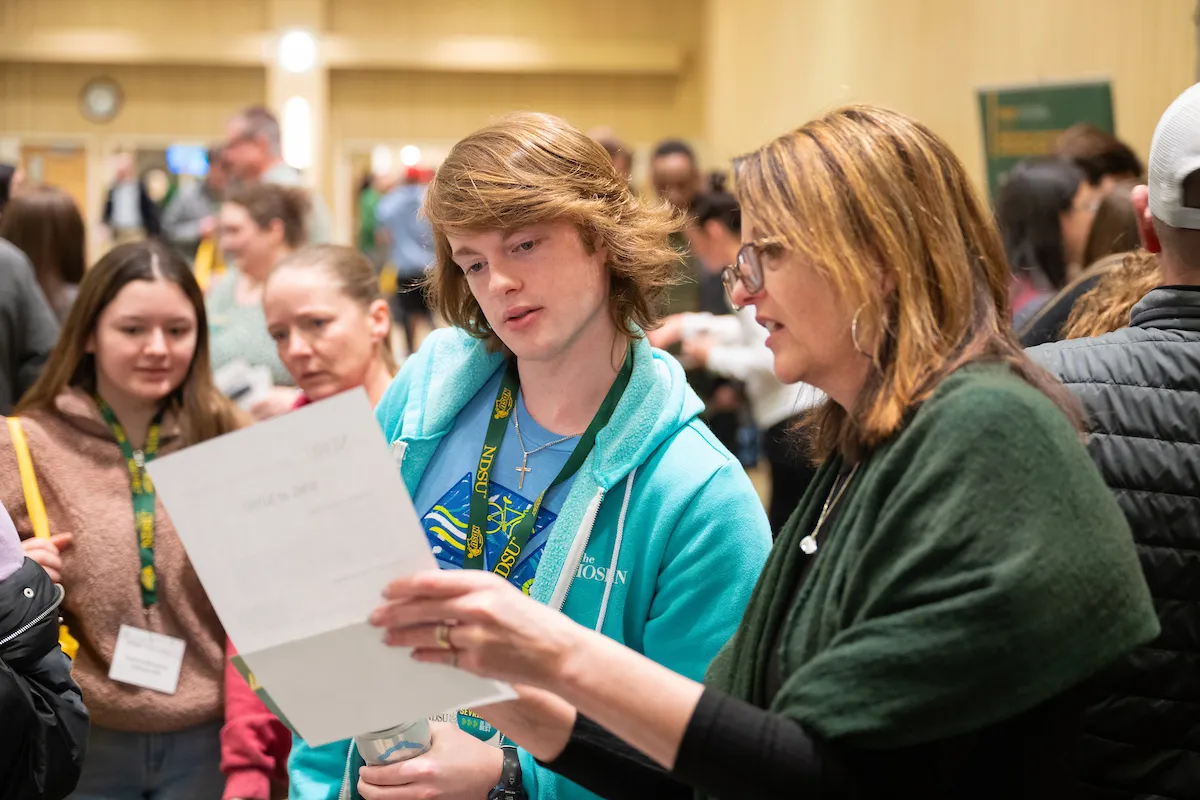 staff member helps student guest at discover days event