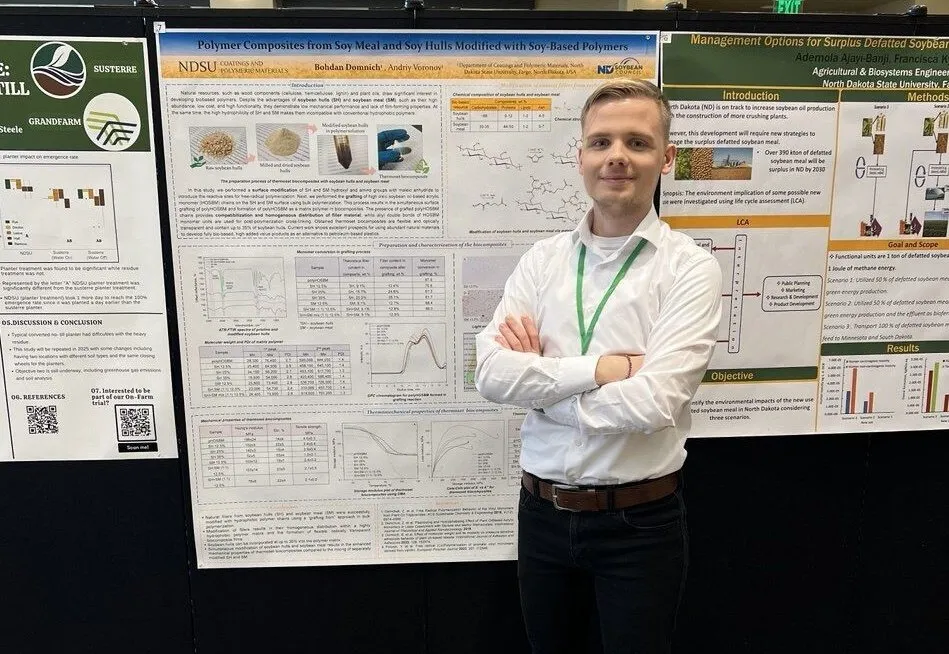 Bohdan Domnich standing infront of his research poster smiling confidently at the camera