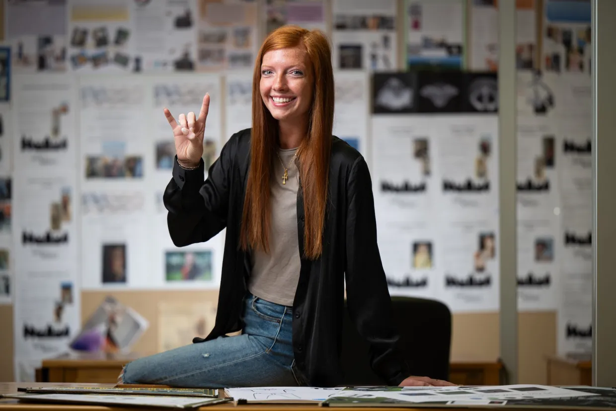 Student smiling confidently at camera with horns up!