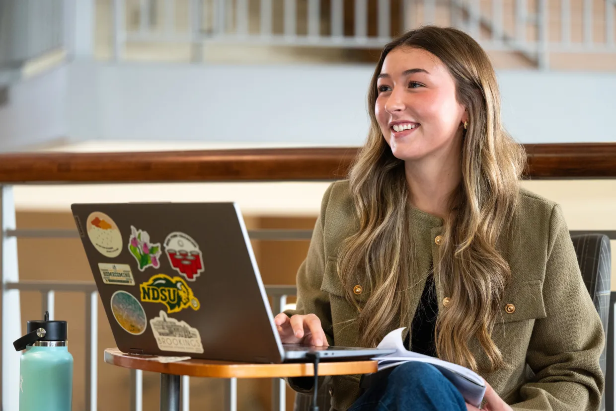Student sitting with laptop open, smiling