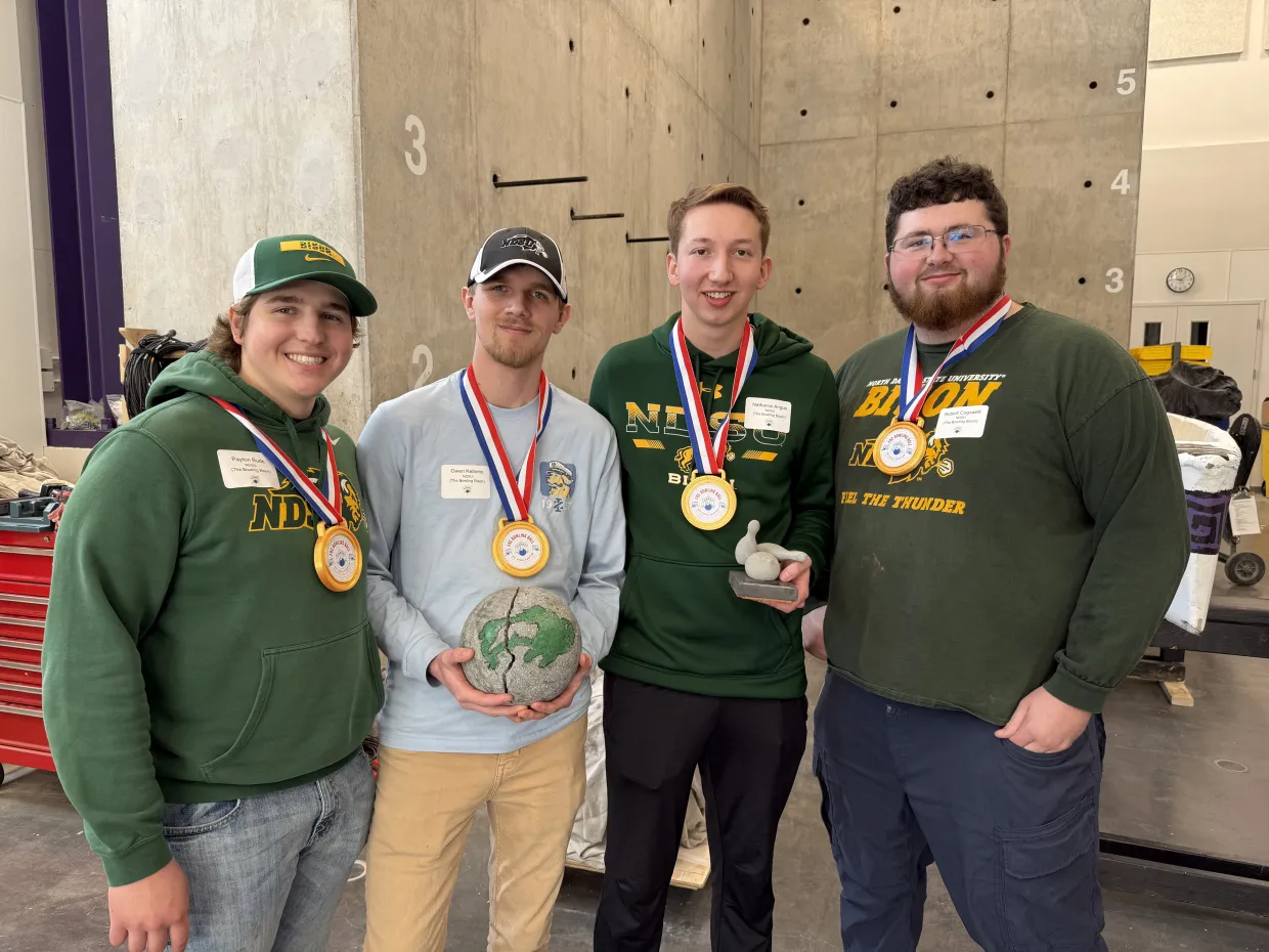 Picture of the winners of the competition, pictured with the concrete bowling ball.