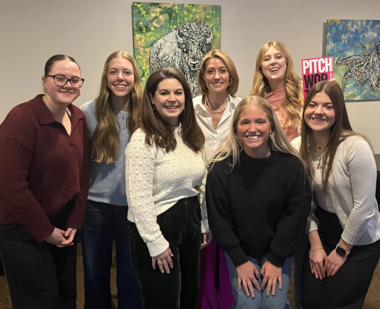 Six girls sitting at a table, smiling for the camera.