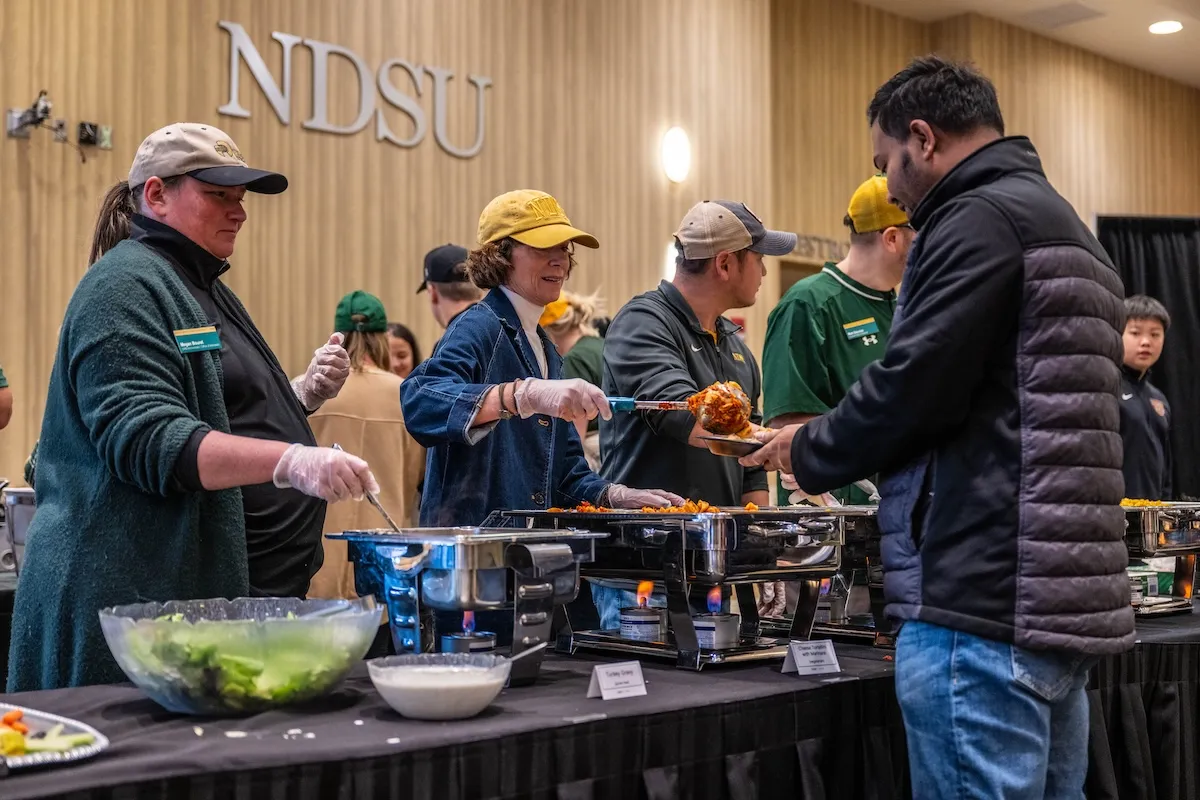 NDSU staff and Kate Cook serve Thanksgiving meal.