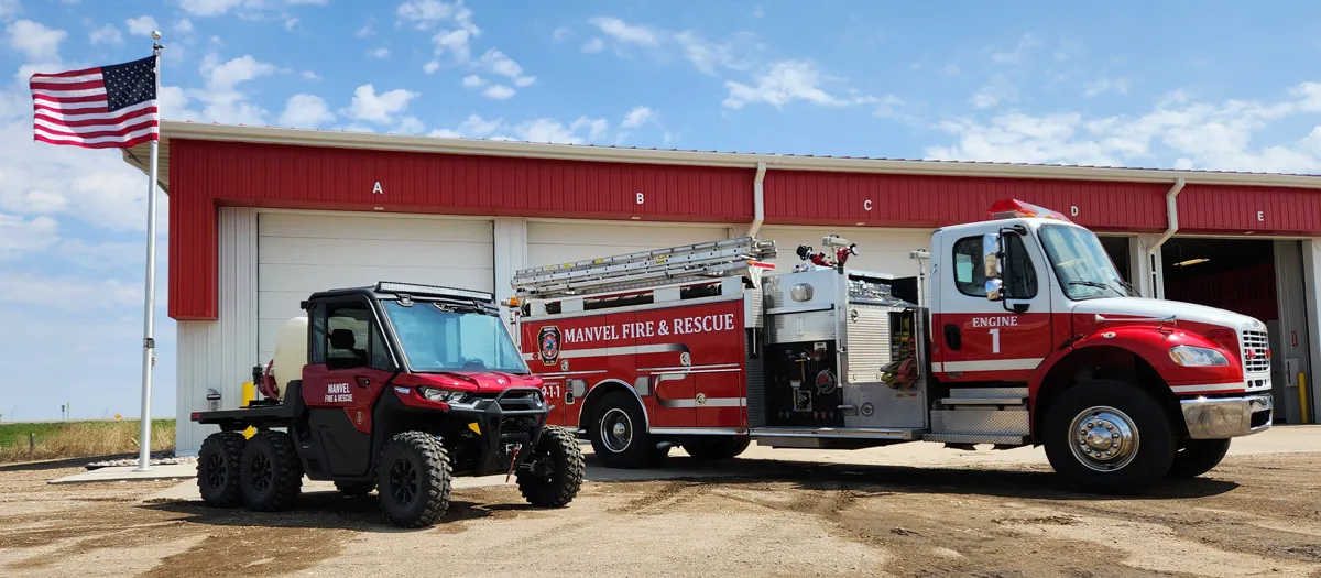 A fire truck and a UTV are parked outside of a fire department