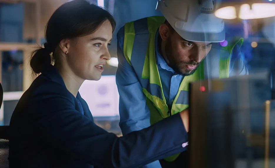 Two manufacturing professionals looking at plans on a computer