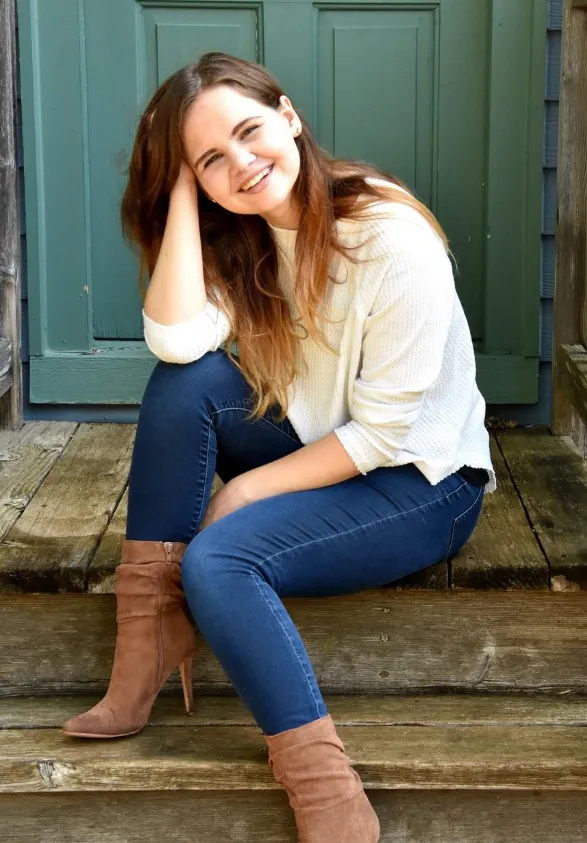 Madison sitting on steps in front of a green door while smiling confidently at camera.