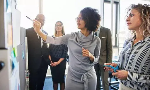Woman presenting ideas on a wall bulletin board to a group of people