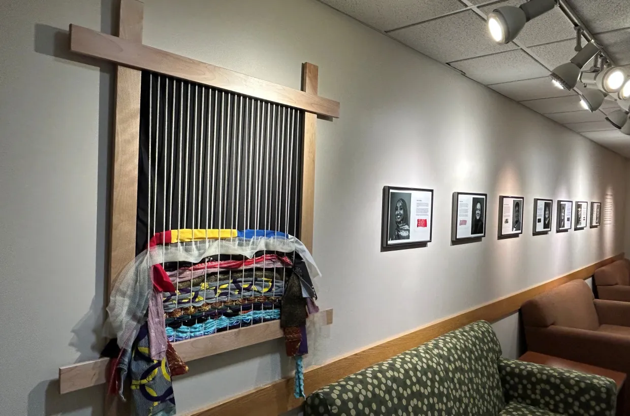 Colorful fabric woven into loom that is attached to the wall.