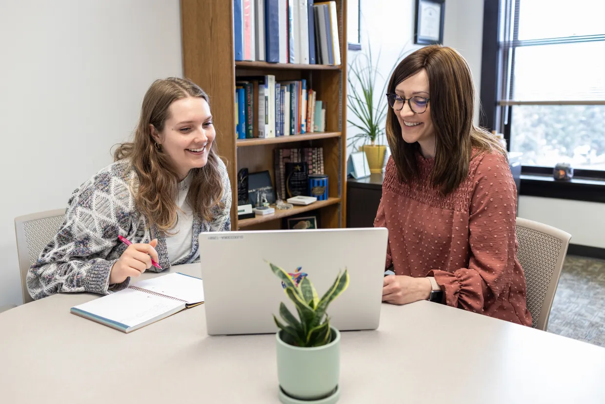 A student works with a staff member on their laptop at the Career and Advising Center.
