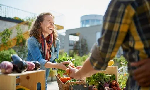 Vegetable Stand worker smiling and handing vegetables to customer