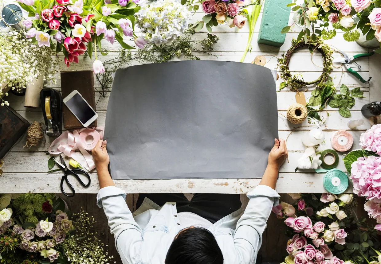 Person working on flower arrangements on a big table