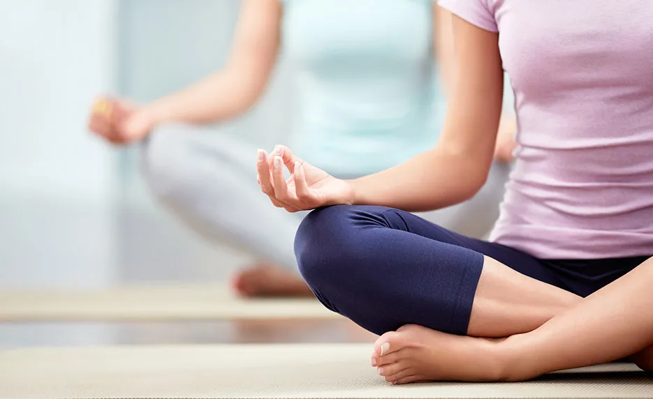 Two people sitting cross-legged in yoga pose