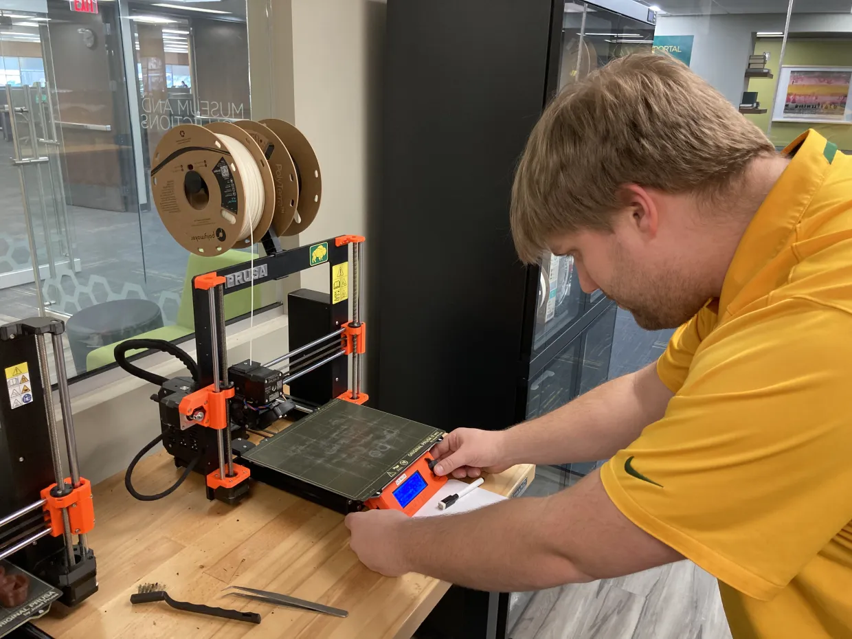 NDSU Library employee Zachary Drechsel preparing to 3D print a harpsichord tongue in the Digital Fabrication Lab.