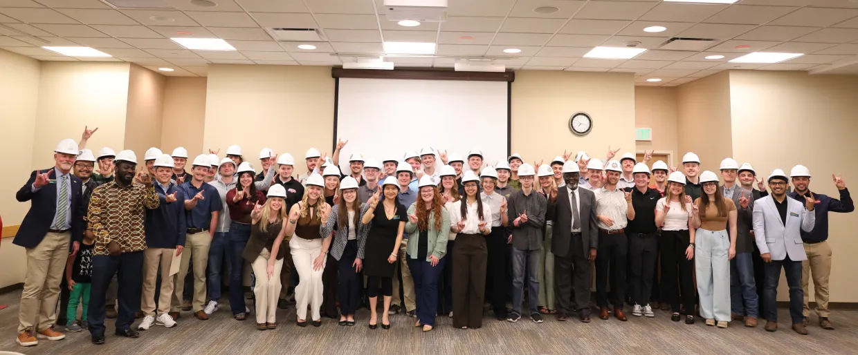 CCEE Department Seniors smiling and holding up the Bison horns for a photo with their hard hats.