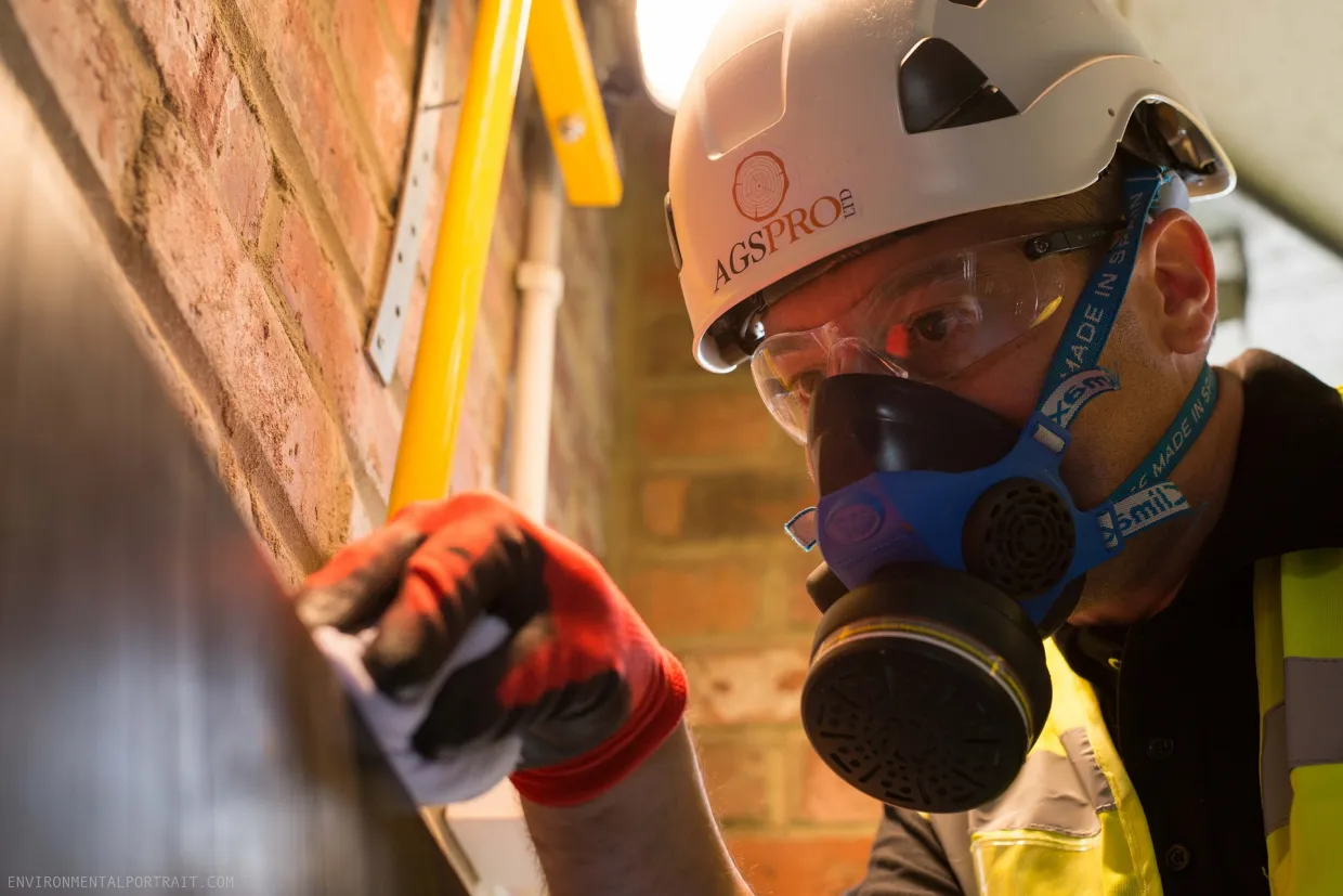 Home inspector with Helmet and breathing mask on measuring a wall