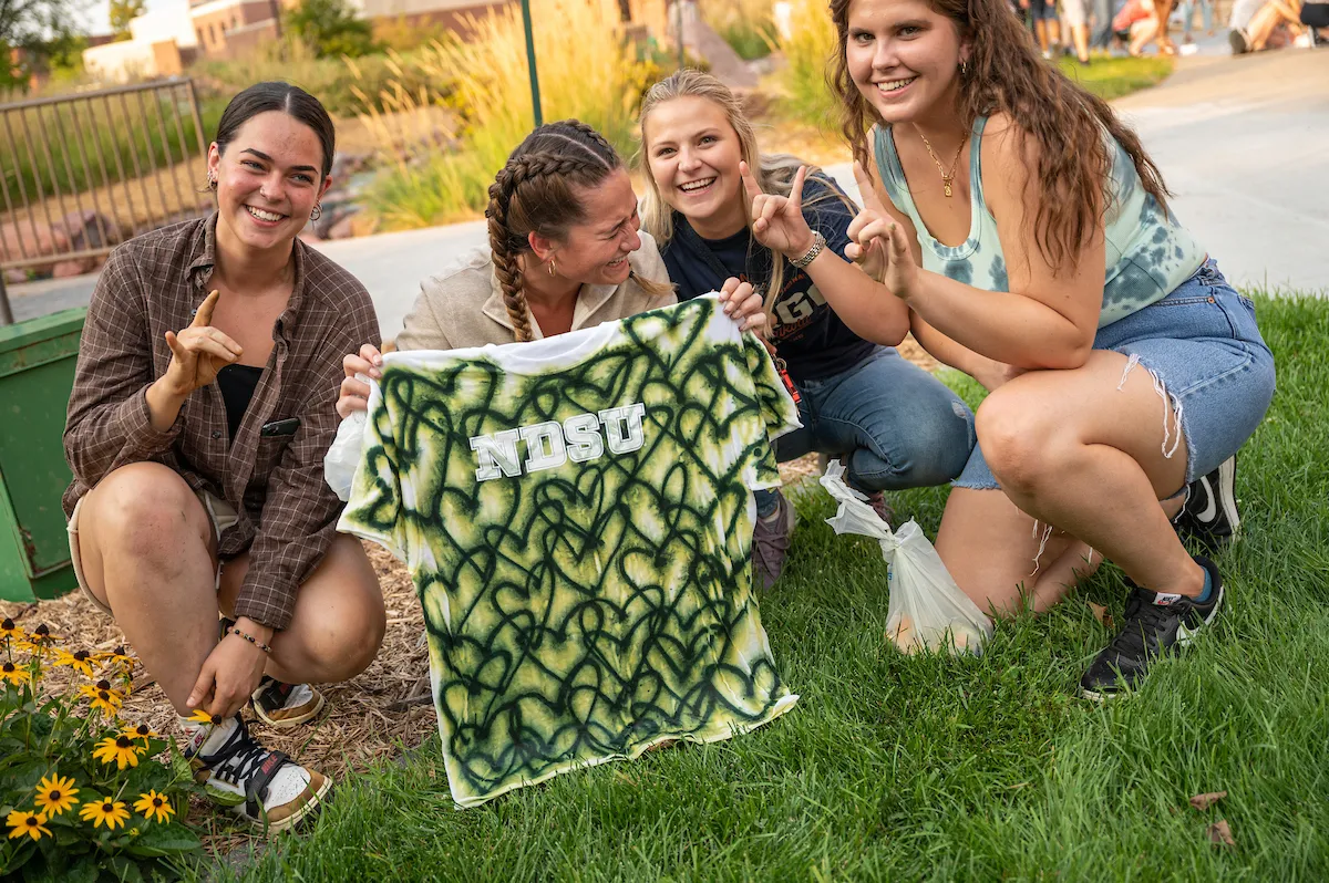 A group of NDSU students show off their NDSU heart tie-dye shirt.