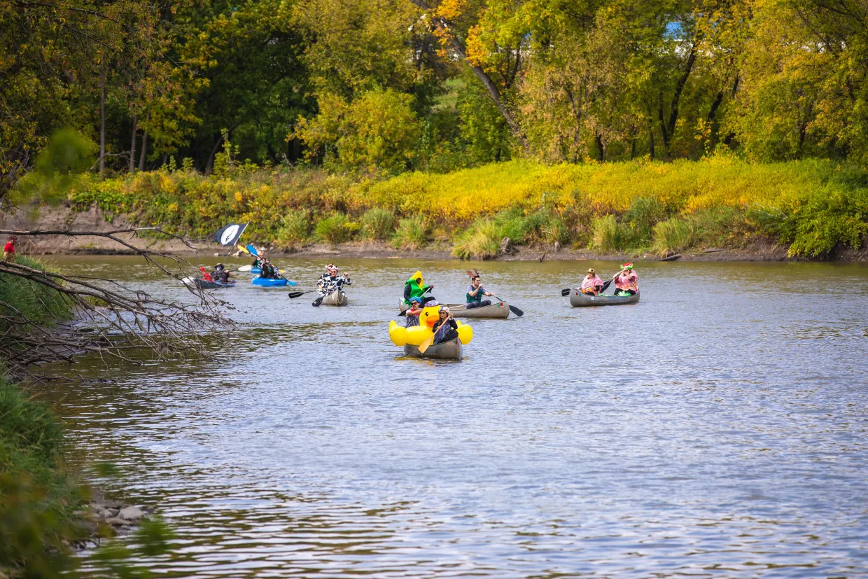 People in kayaks drift down a river