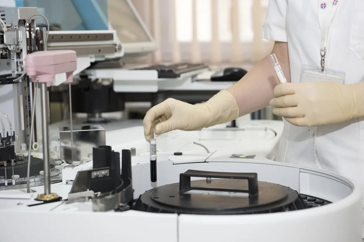 healthcare lab employee putting bio sample in a machine for testing