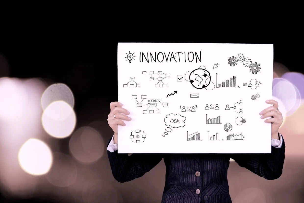 Business person in a suit, holding up a poster of a light-bulb, org chart, idea and the word innovation