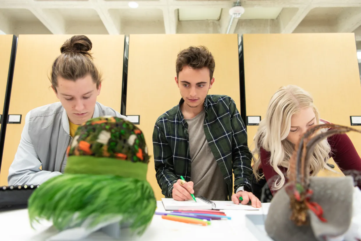 Students working with hats displayed on table.