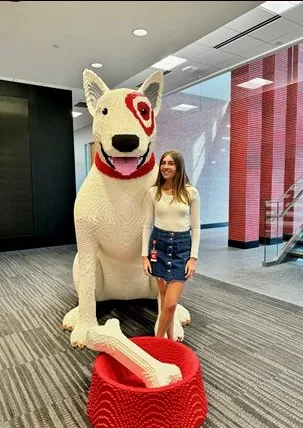 Ashley standing next to large Lego Target dog while smiling confidently at camera.