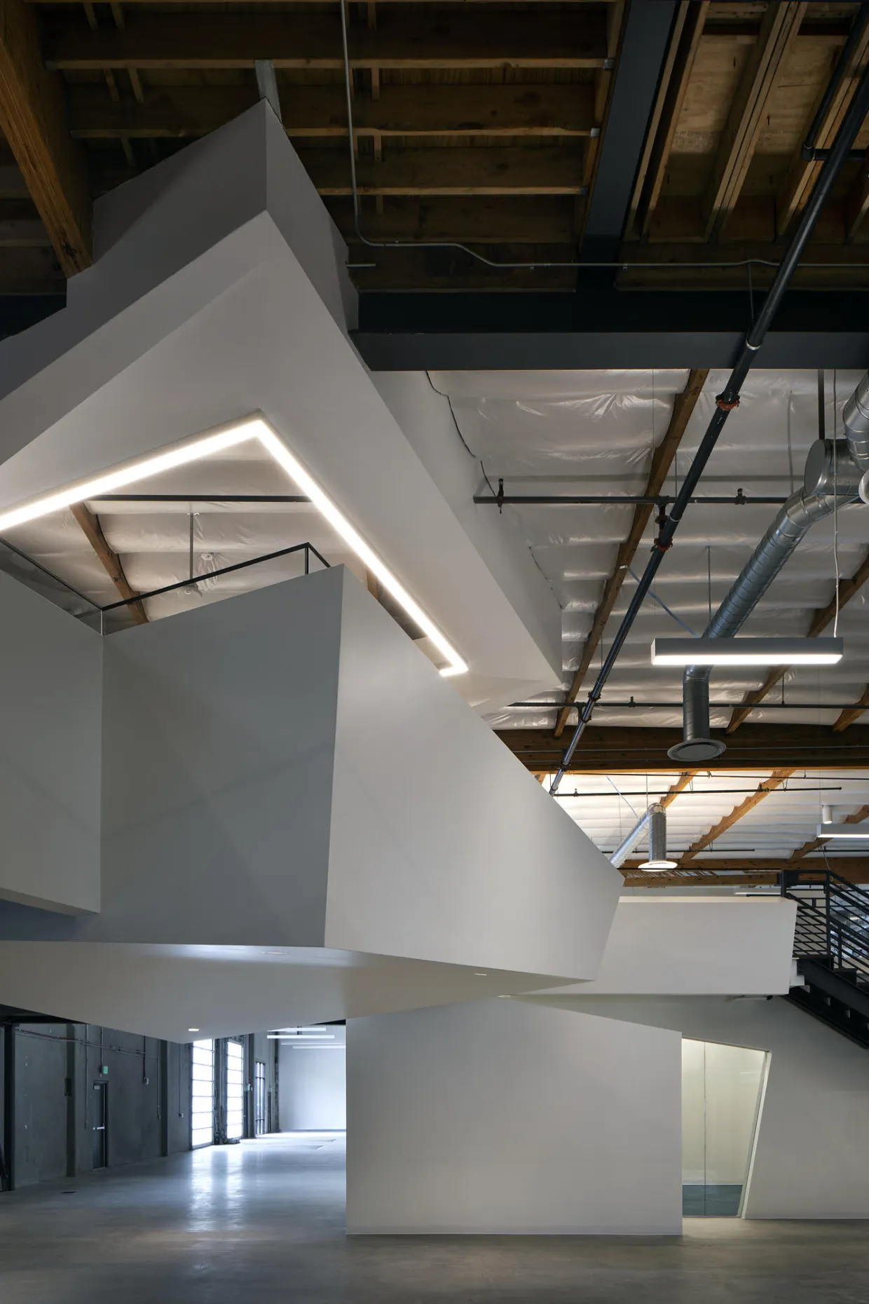 Interior of a modern building with white walls and exposed ceiling joists.