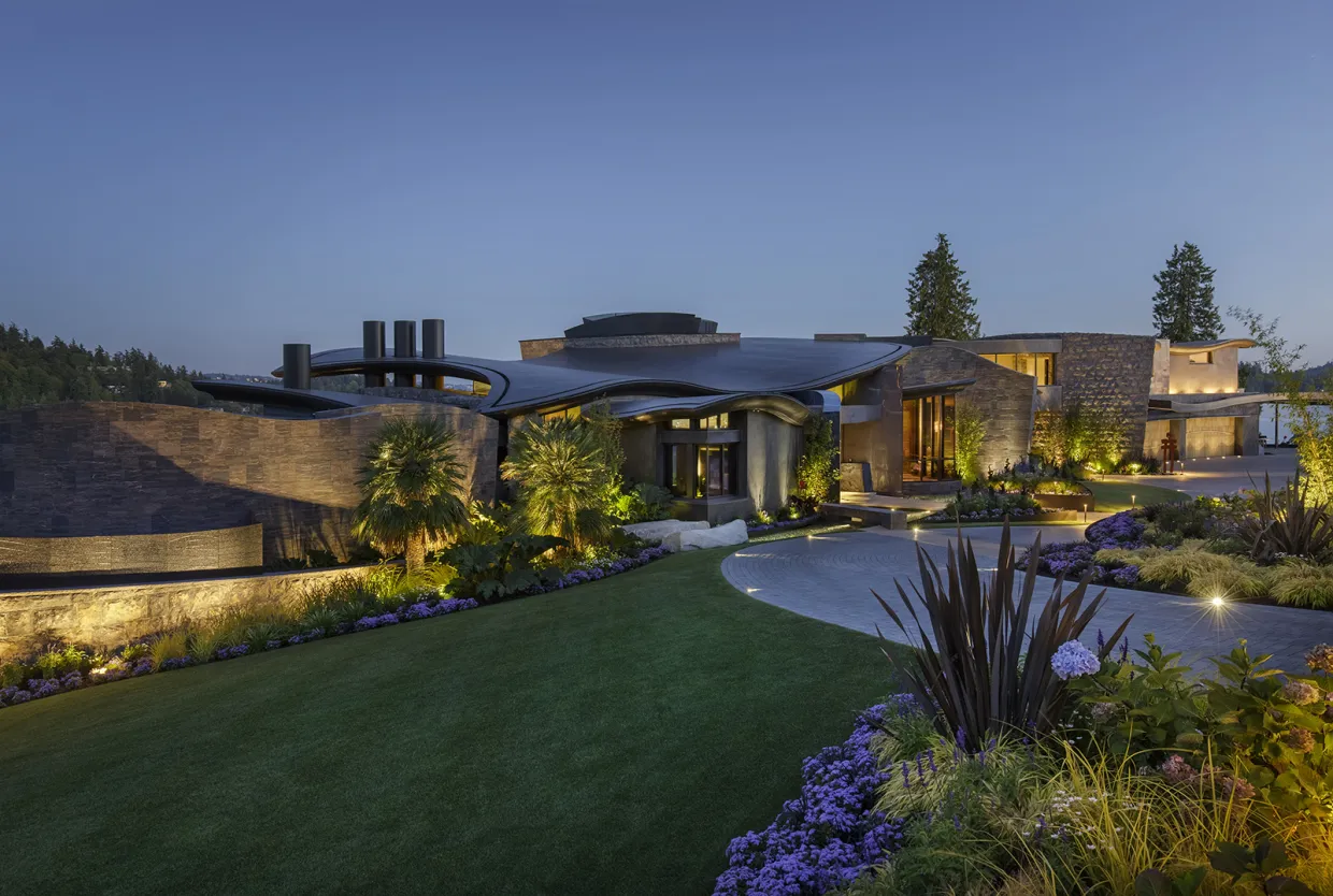 Large home with palm trees, flowers and green grass.