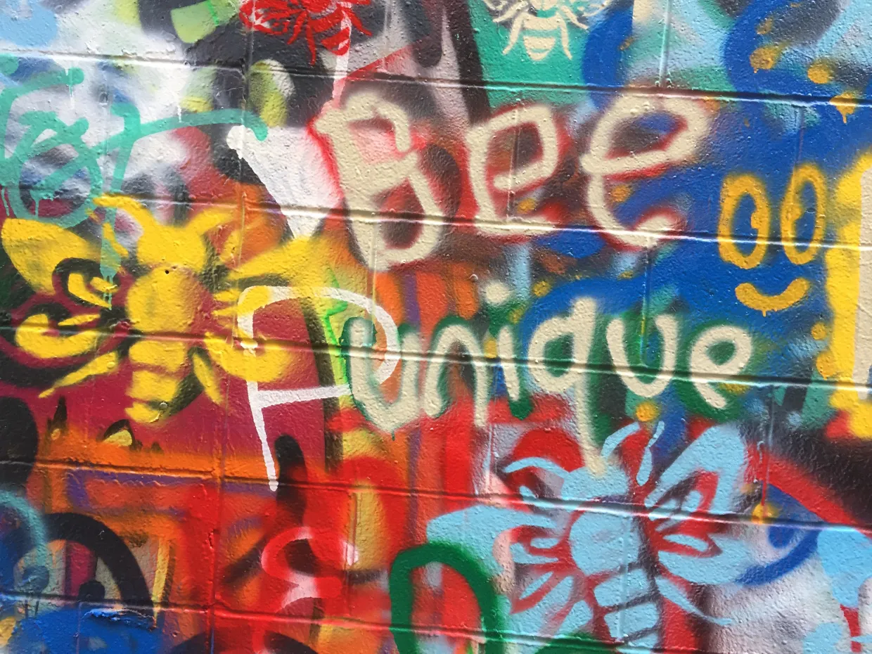 Graffiti wall with ‘Be Unique’ written in bold letters and colors. 