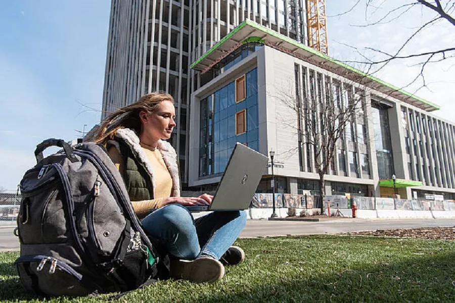 CCEE student sitting outside on the lawn of a building under construction.