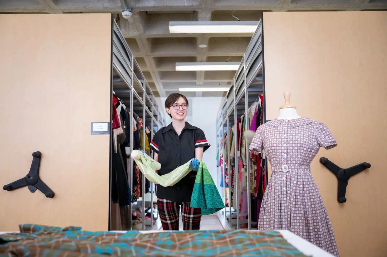 Student holding a dress from the Emily Renolds collection.
