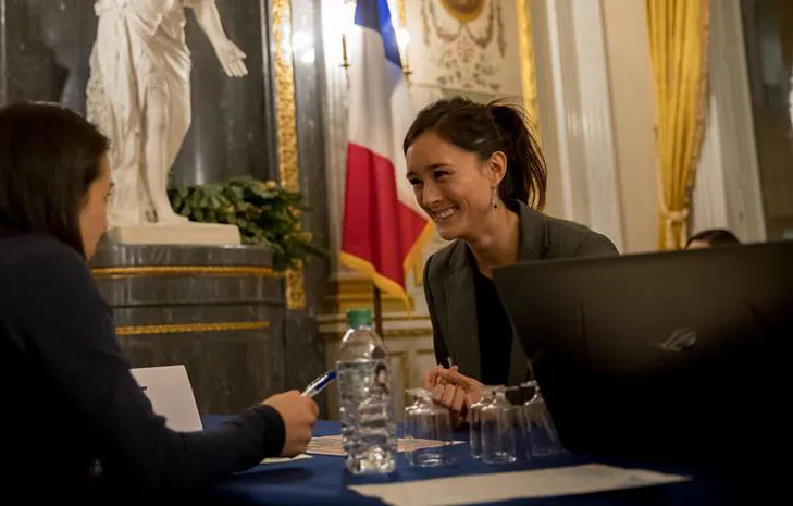 April Lipatan smiling at person sitting opposite of her at table. 