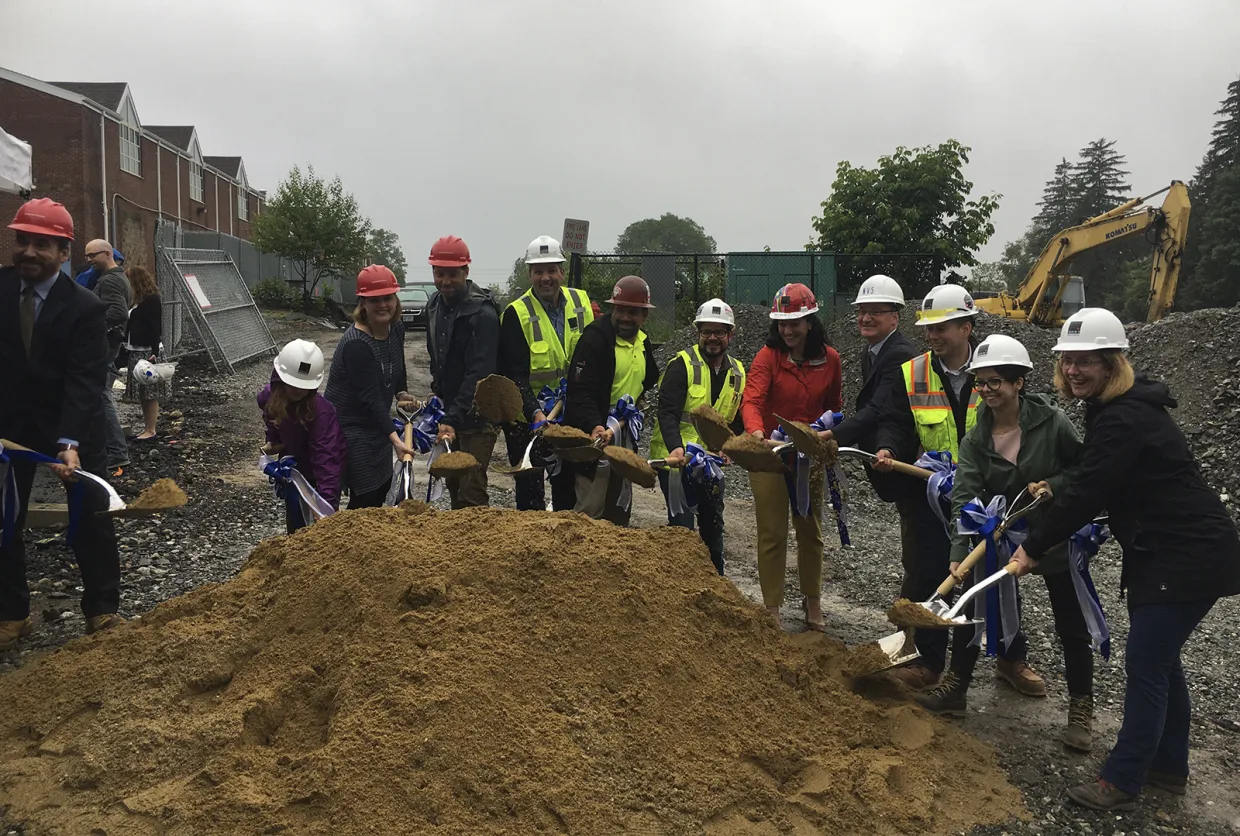 A group of people holding shovels with dirt for a ground-breaking ceremony.