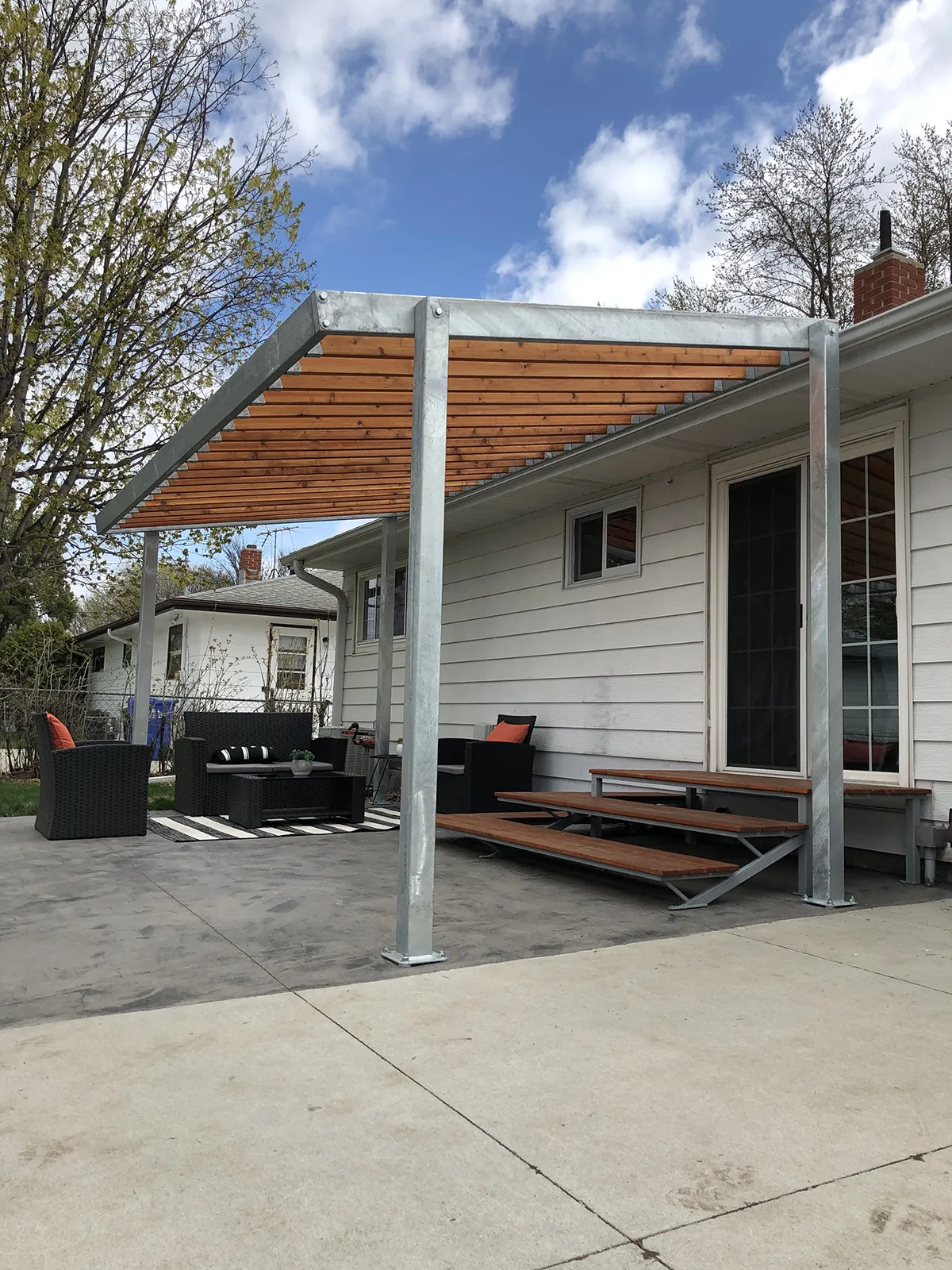 Pergola made of wood beams and steal supports covering a patio.