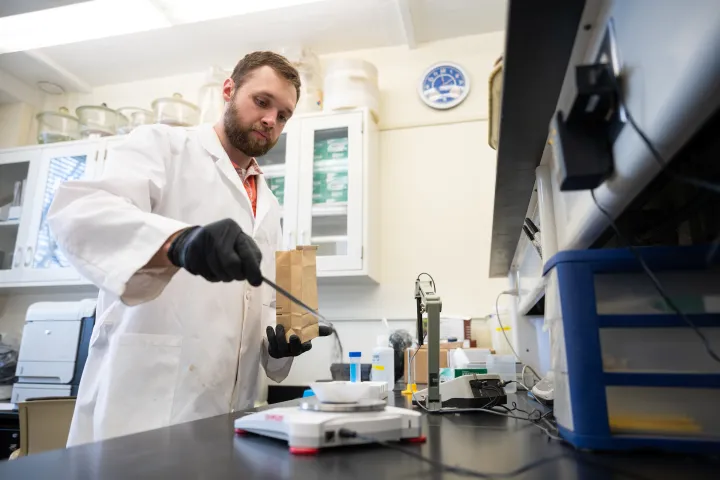 student weighing samples of dirt on a scale