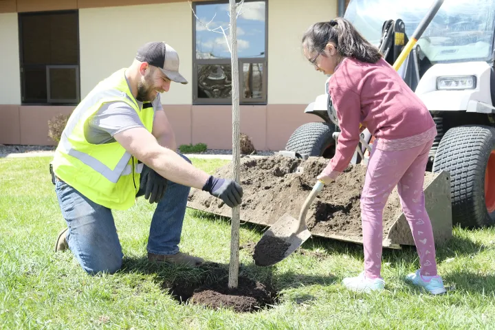 A man and a young girl plant a tree