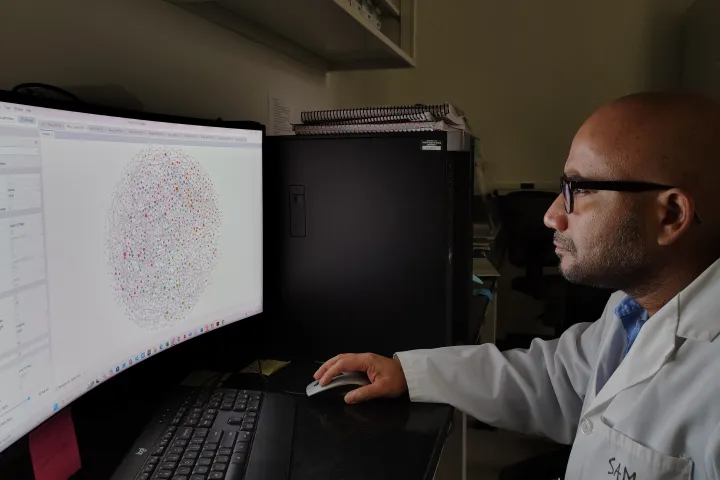 Samiran Banerjee, NDSU assistant professor of microbial ecology, sits in his lab while looking at a graph on a computer.