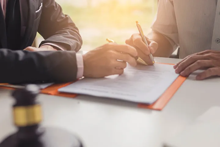 Two individuals with pens, editing a grant