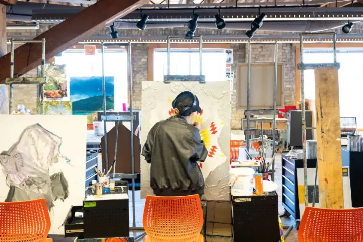 An NDSU student working on a mixed media artwork in a studio