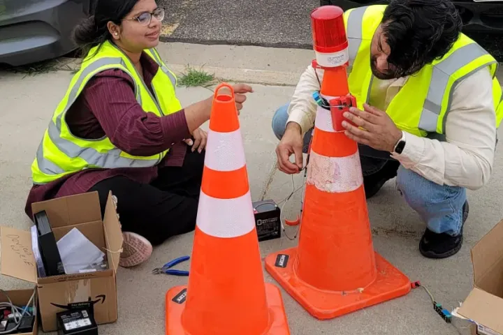 2 students put sensors on highway safety cones as part of a research project