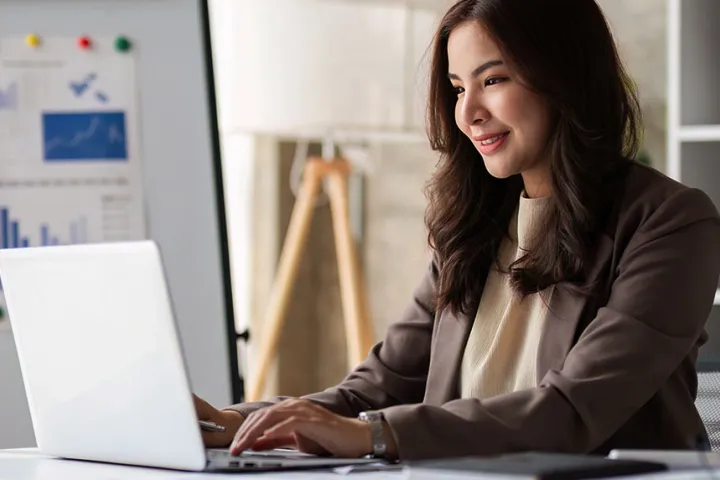 Woman working on a laptop with business charts in the background