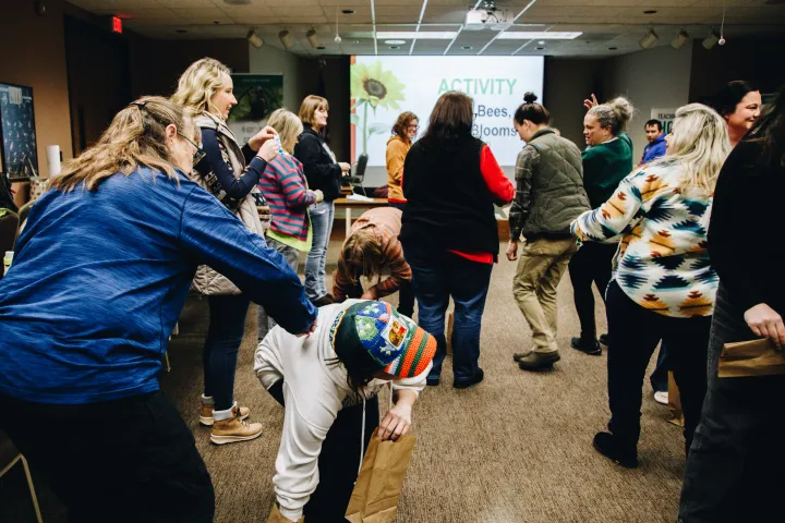A group of people play a game where they emulate how pollinators collect nectar from flowers and how flowers share their pollen